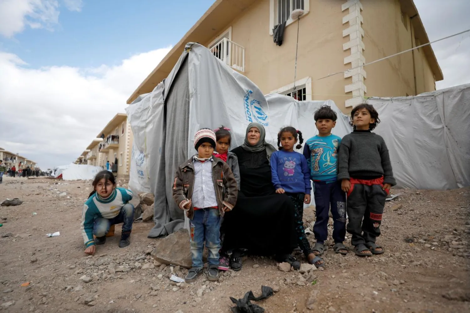 Amira Gharmoush sits with her grandchildren outside a tent in Herjelleh shelter in Damascus countryside, Syria March 30, 2018. (Reuters)