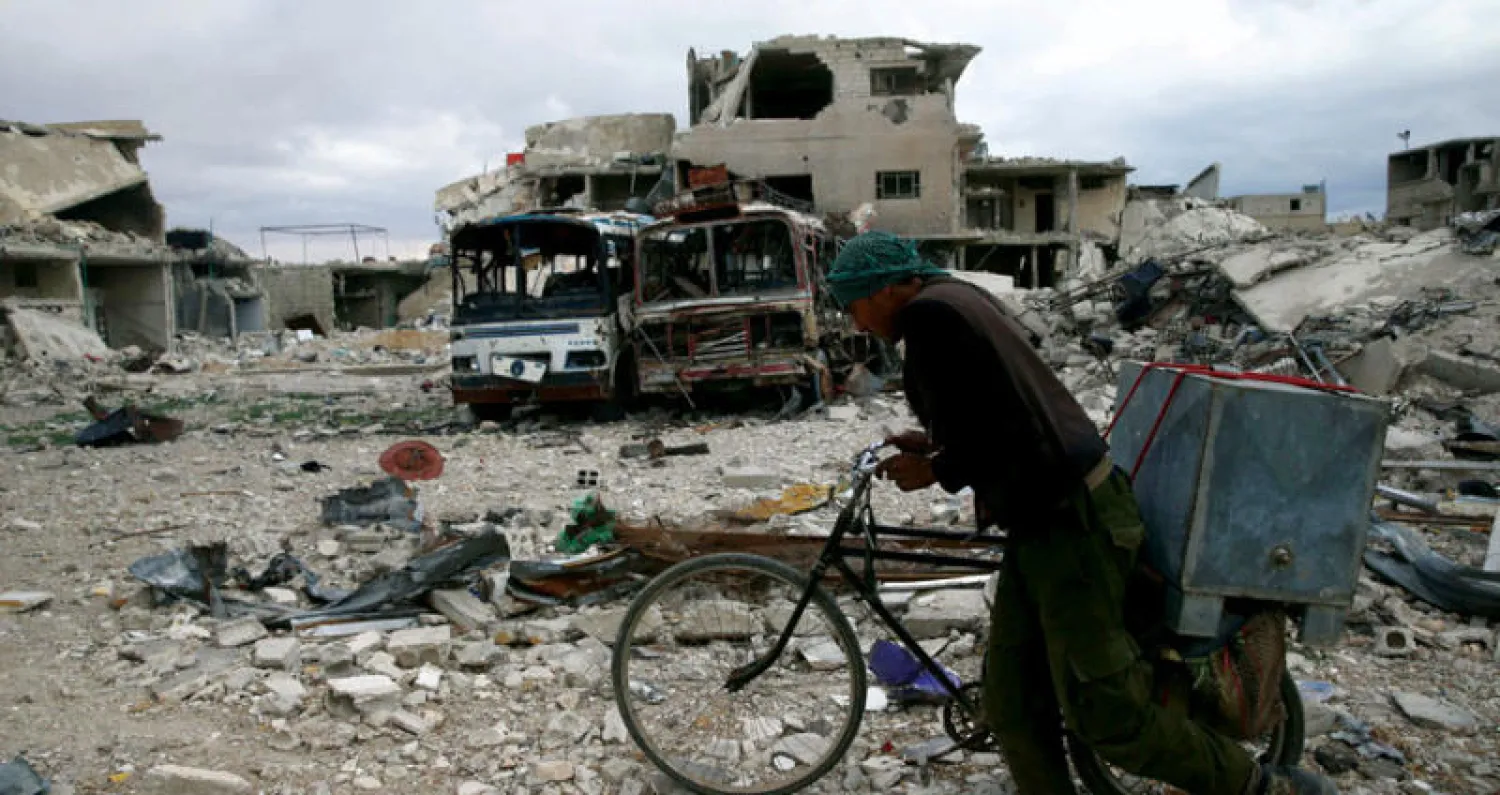 رجل على دراجته يجتاز البيوت المهدمة في الغوطة الشرقية لدمشق (رويترز)