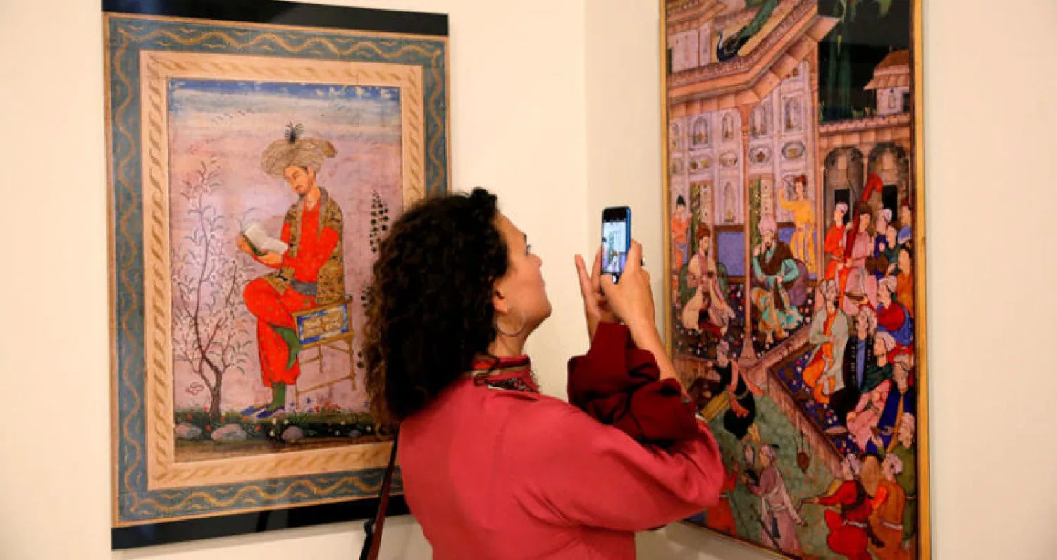 امرأة تلتقط صوراً في معرض فني في حديقة بابور في كابل (رويترز)