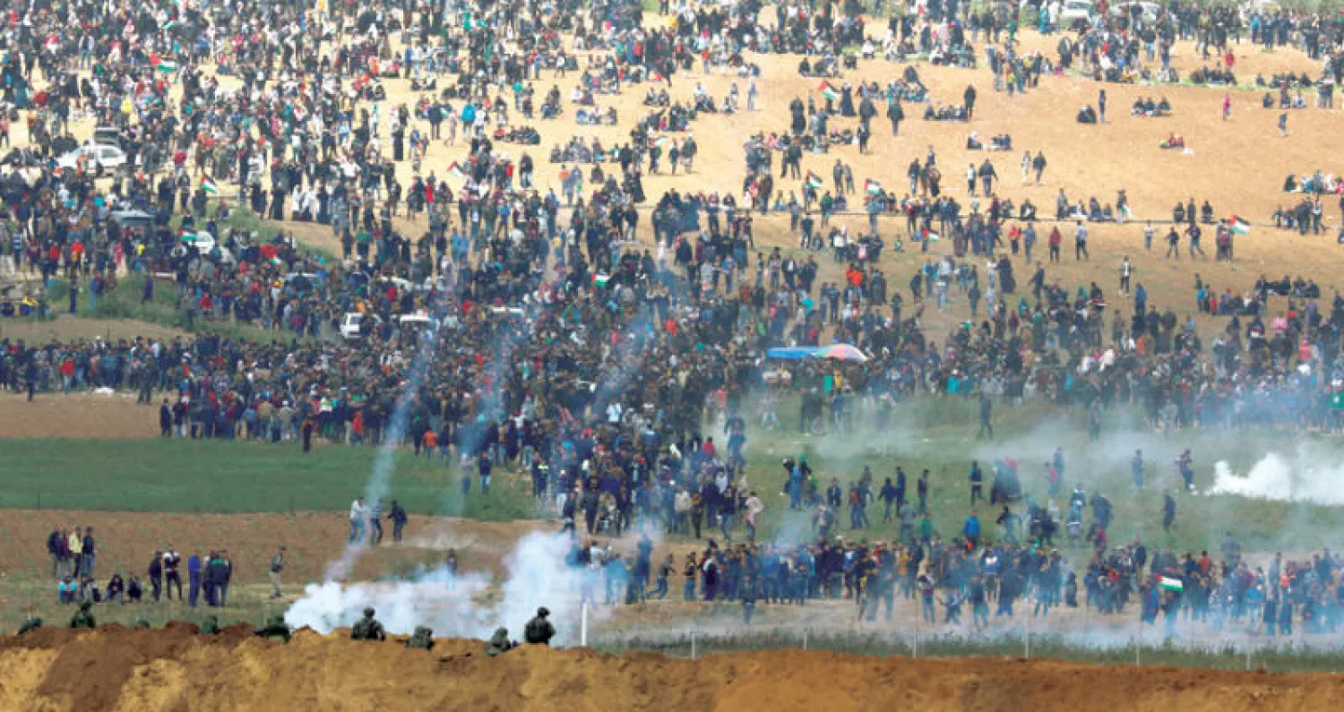 جنود الاحتلال يطلقون قنابل الغاز باتجاه المتظاهرين على الحدود مع غزة (رويترز)