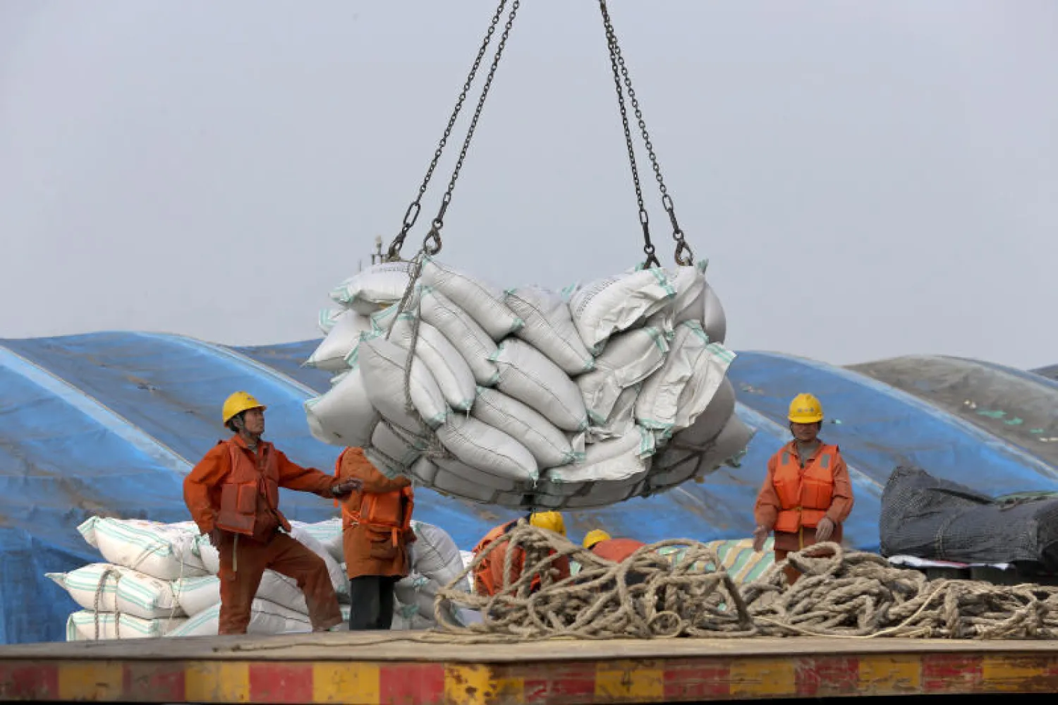 عمال يفرغون حمولة من فول الصويا بميناء نانتونغ في إقليم جيانغسو شرق الصين (أ.ب)