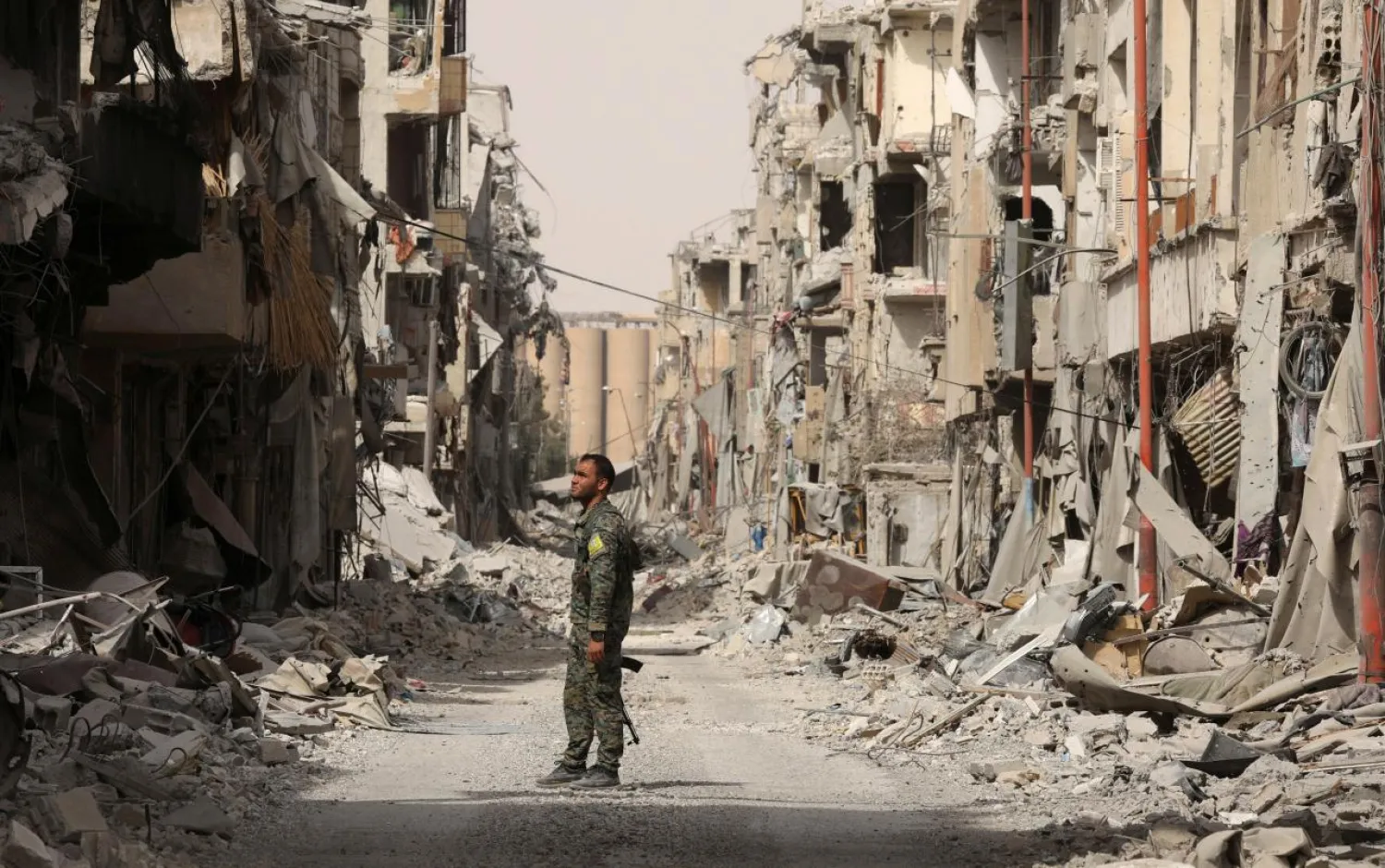 A fighter from the Syrian Democratic Forces stands next to debris of damaged buildings in Raqqa, Syria in September 2017. (Reuters)