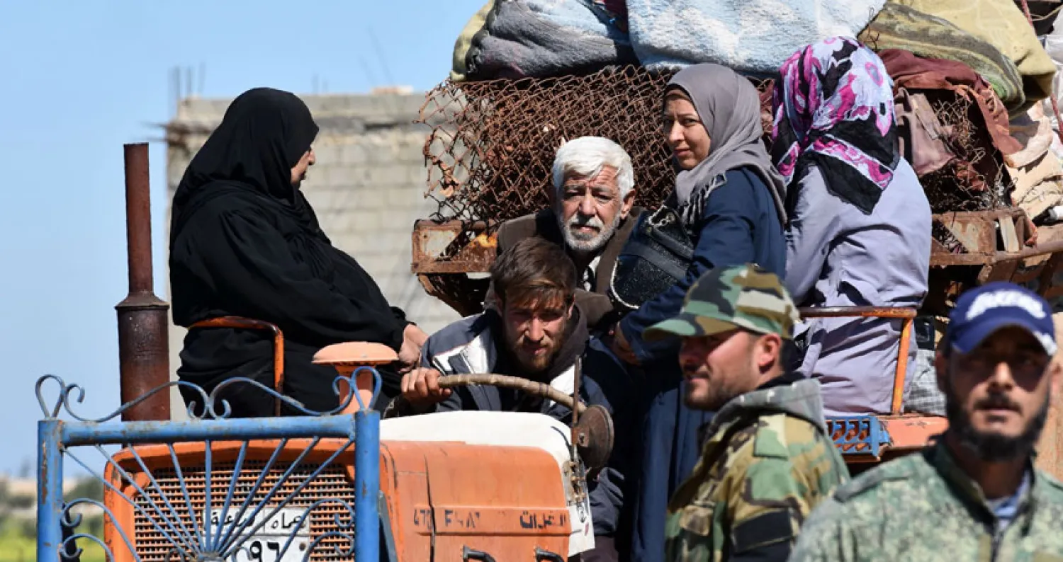 نازحون لدى وصولهم إلى نقطة تفتيش تابعة للنظام في طريق عودتهم إلى منازلهم في إدلب أمس (أ.ف.ب)
