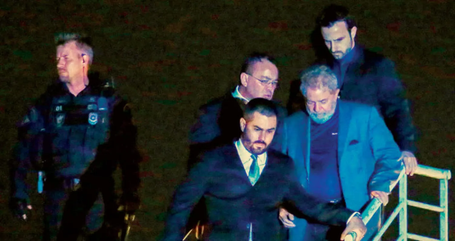 لولا (وسط) لدى وصوله إلى مقر الشرطة الفيدرالية في كوريتبيا الليلة قبل الماضية لبدء تنفيذ عقوبة سجنه (أ.ف.ب)