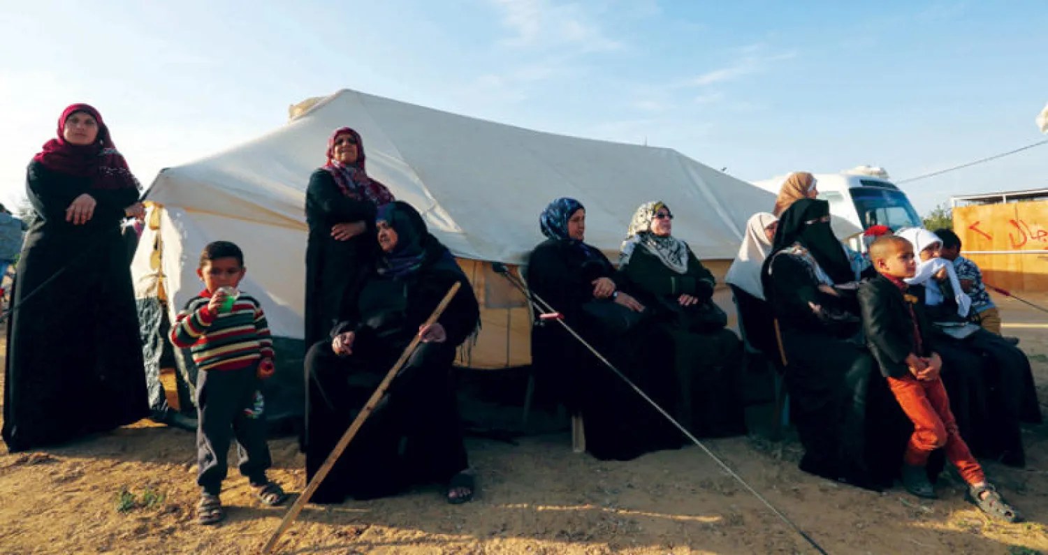 فلسطينيات يجلسن أمس قرب «خيام العودة» على حدود قطاع غزة مع إسرائيل (أ.ف.ب)