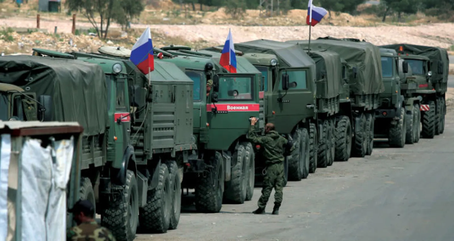 جنود روس ينتظرون عند مدخل «مخيم الوافدين» وصول سيارات لنقل مقاتلي «جيش الإسلام» من دوما أمس (أ.ف.ب)