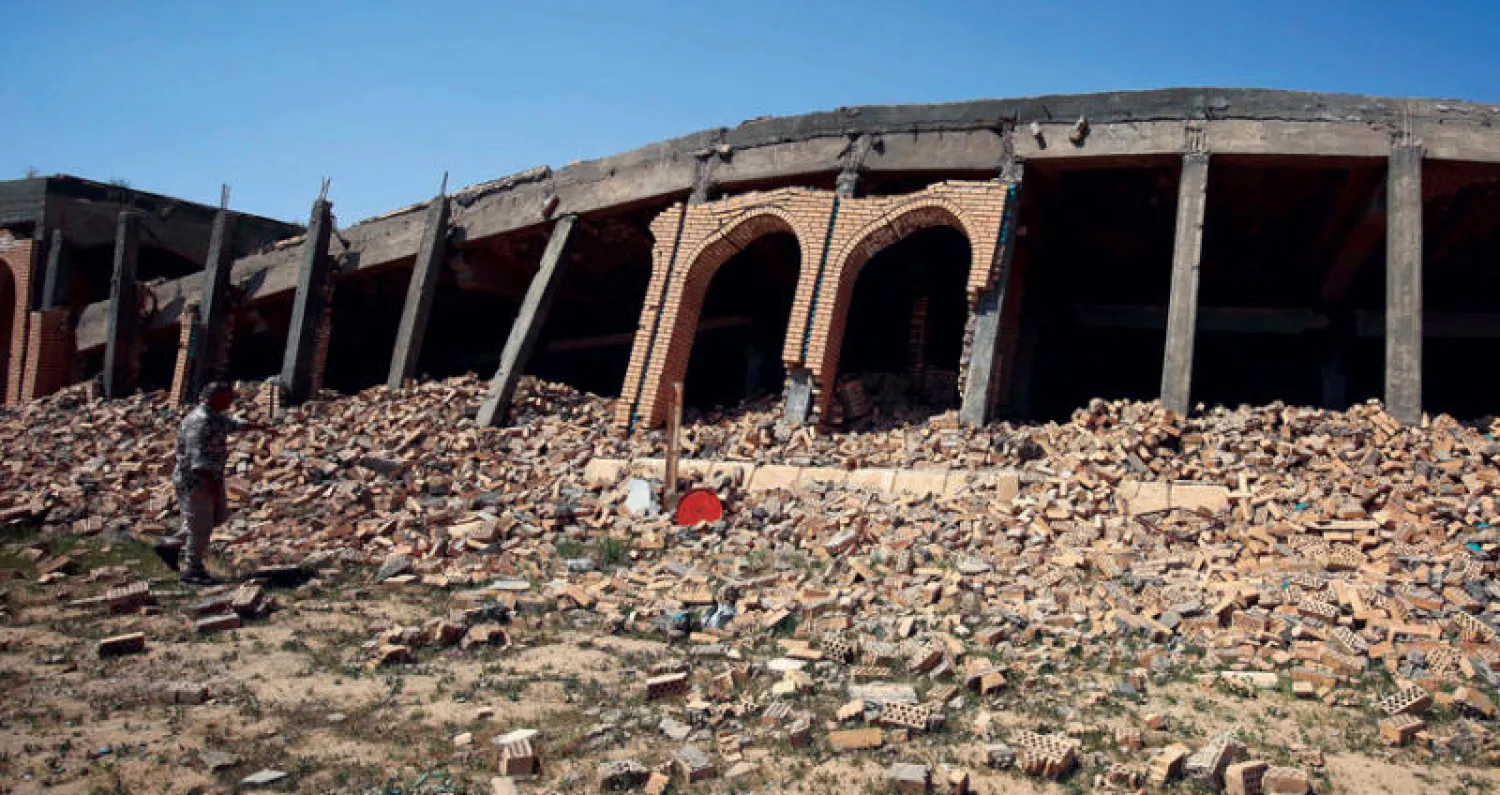 عنصر في «الحشد» أمام ركام مقبرة الرئيس العراقي السابق صدام حسين في قرية العوجة قرب تكريت (أ.ف.ب)
