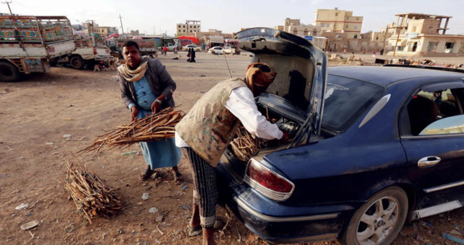 يمنيان يضعان حزم الحطب التي اشترياها في سيارة بصنعاء أمس في ظل ندرة الغاز في السوق (إ.ب.أ)