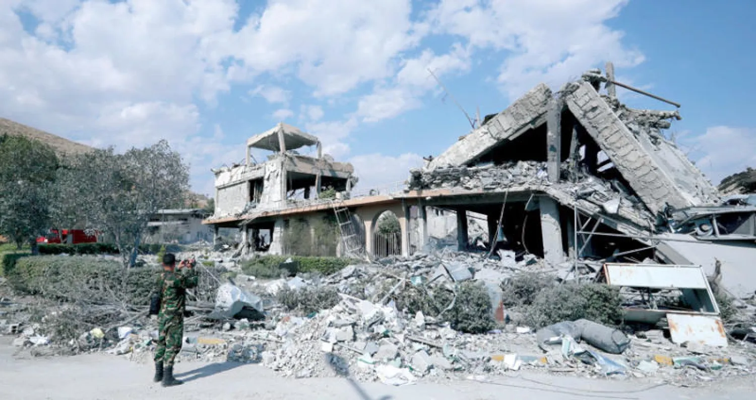 عنصر من قوات النظام في ضاحية برزة يلتقط صوراً لمركز البحوث العلمية المدمر اثر الغارات (أ. ب)