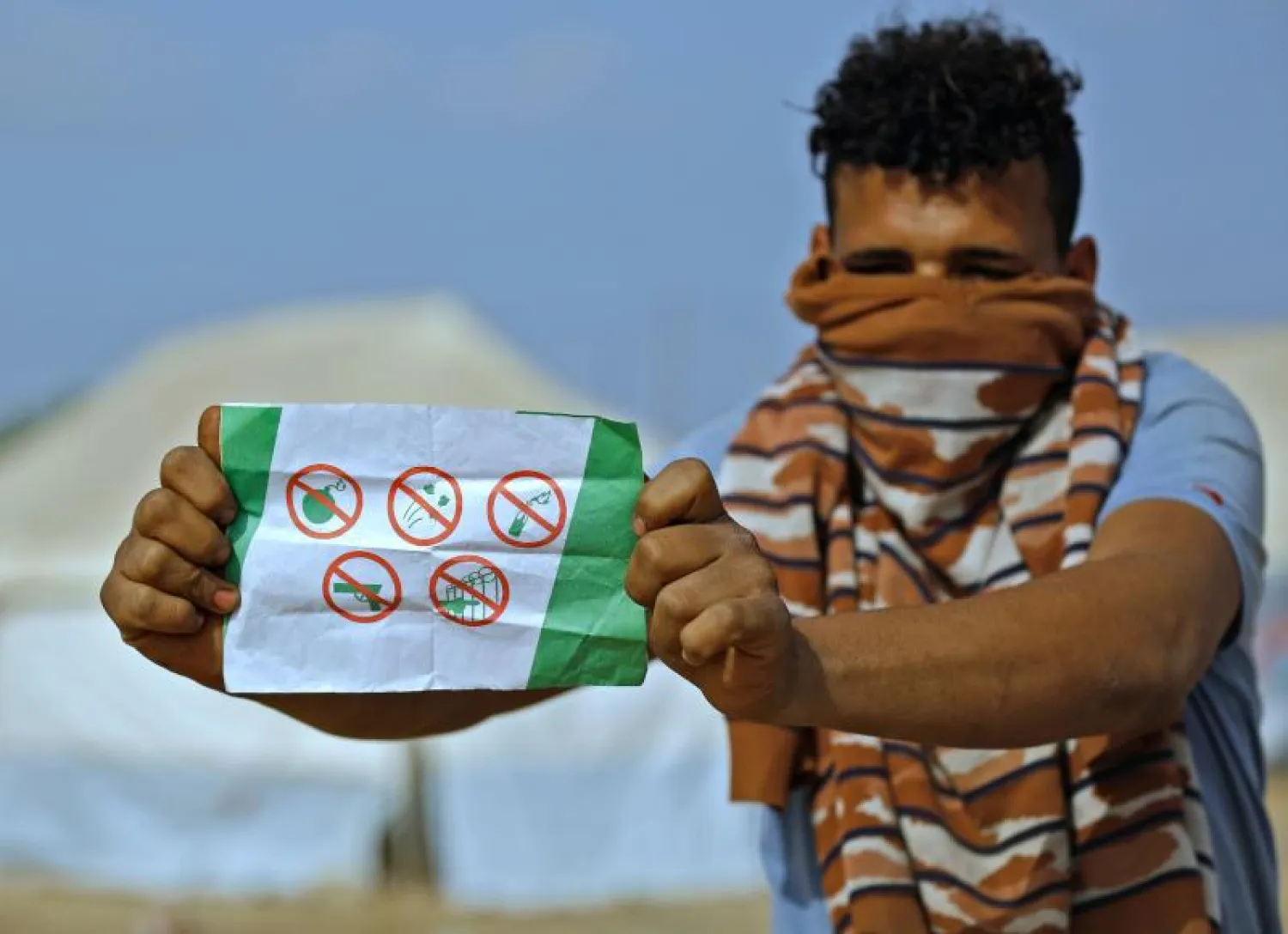 شاب فلسطيني يعرض منشور ألقاه الجيش الإسرائيلي يحذ أهالي غزة من الاقتراب من السياج الحدودي (أ.ف.ب)