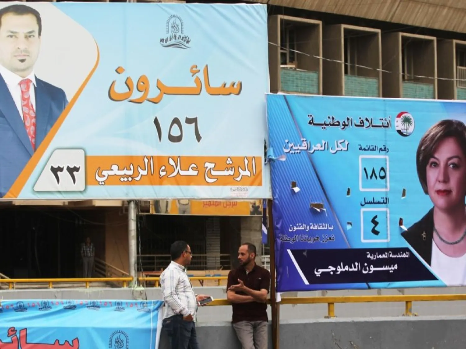 Iraqis stand in front of campaign posters of candidates in upcoming parliamentary elections on April 15, 2018 in Baghdad. (AFP)