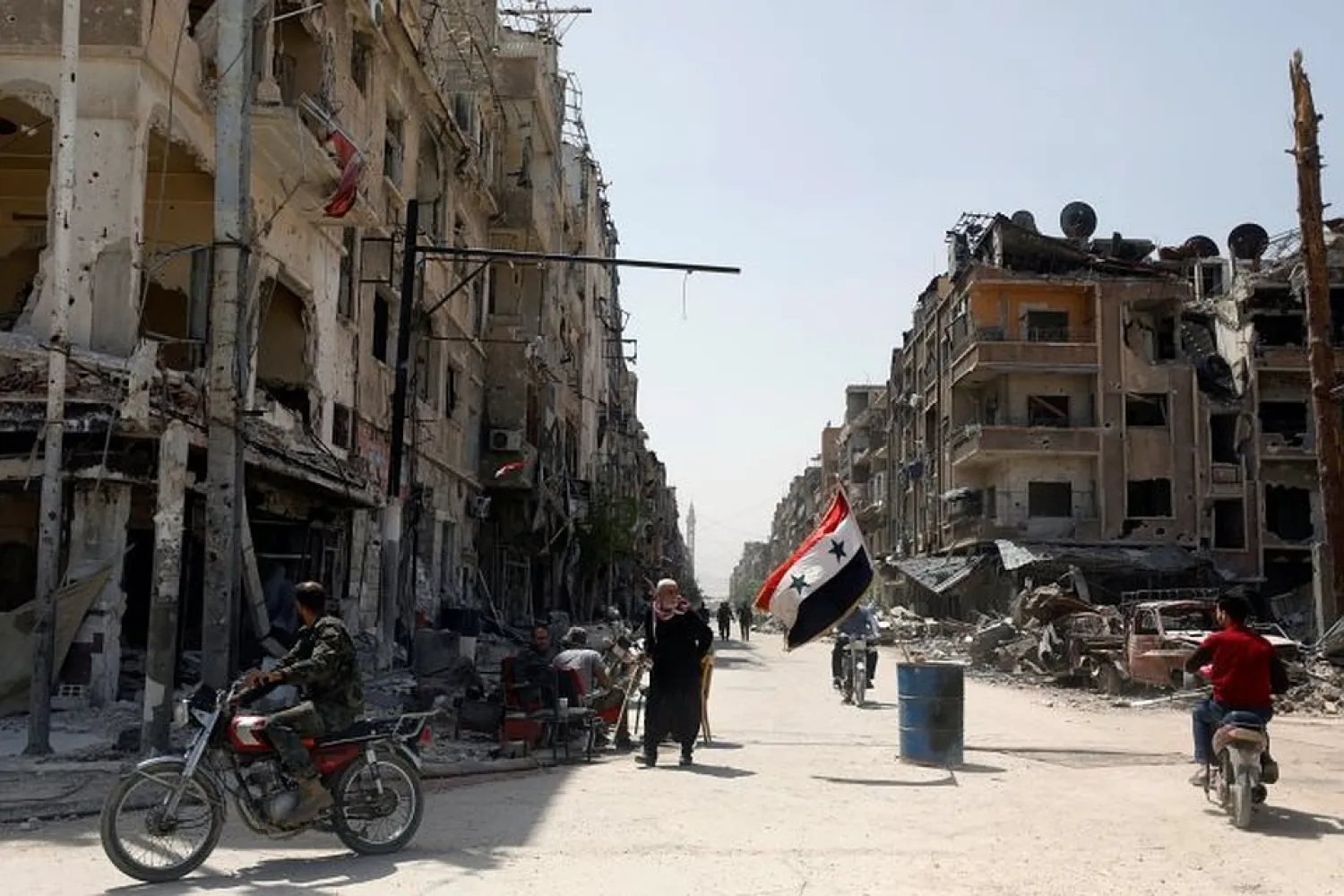  A Syrian flag flutters along a damaged street at the city of Douma in Damascus, Syria, April 20, 2018. REUTERS/Omar Sanadiki