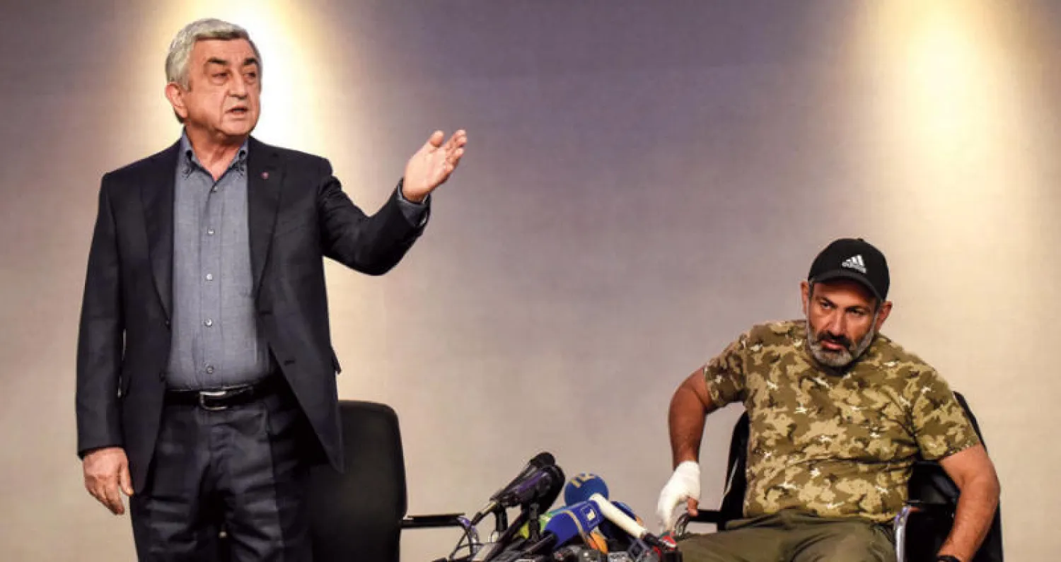 رئيس الوزراء يستعد لمغادرة لقاء تلفزيوني حاد مع رئيس حركة الاحتجاج الذي اعتقل لاحقاً في يريفيان أمس (أ.ف.ب)