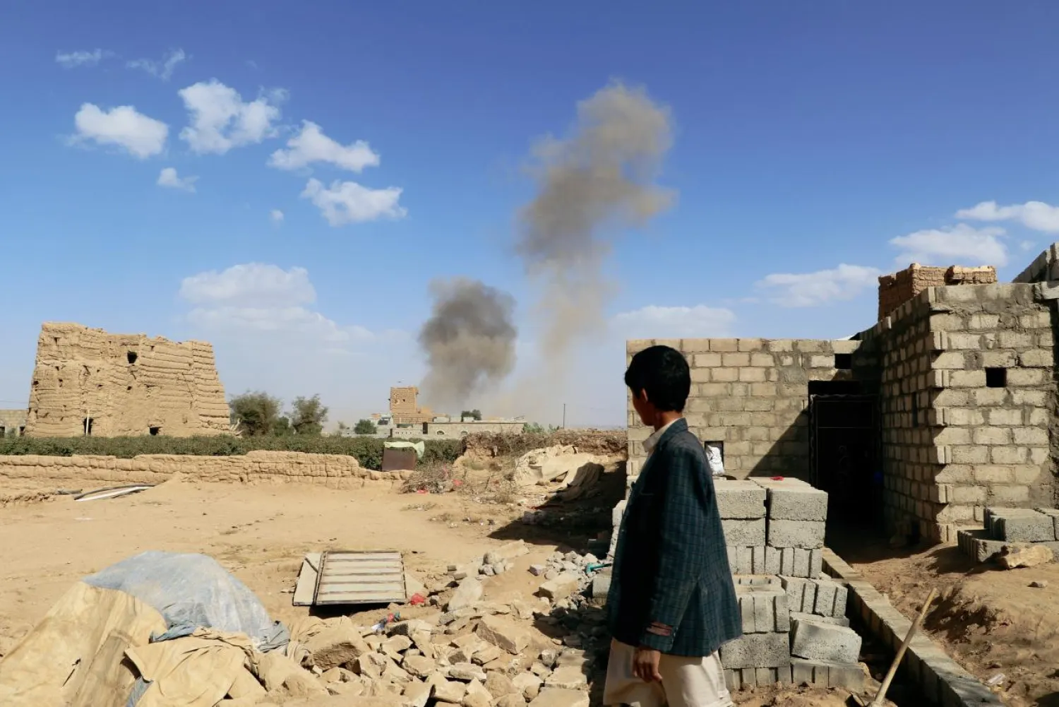 A boy looks at dust raising from the site of air strikes in Saada, Yemen February 27, 2018. Reuters/Naif Rahma