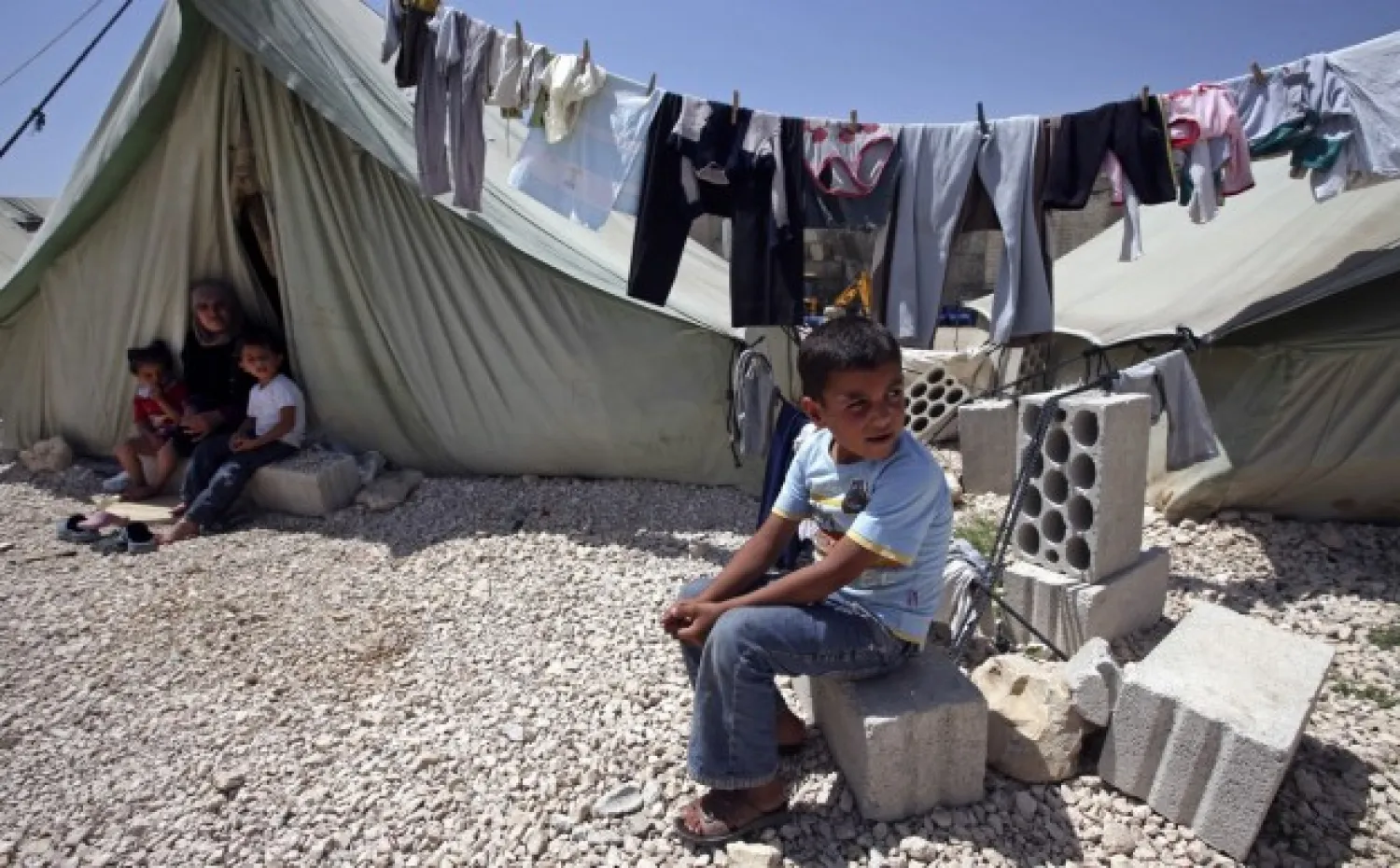 A Syrian refugee boy, right, sits outside his tent next to his family at a temporary refugee camp in the eastern Lebanese town of Marj near the border with Syria, Lebanon, Monday, May 20, 2013. (Hussein Malla/AP)