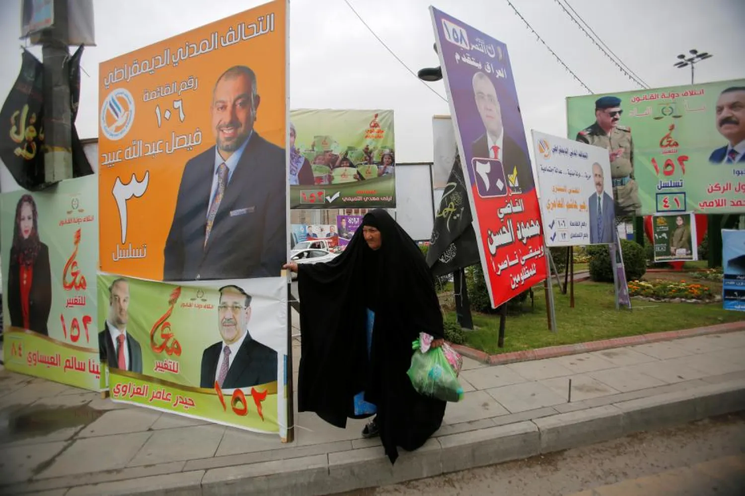 A woman walks past campaign posters of candidates ahead of parliamentary election, in Baghdad, Iraq. (Reuters)