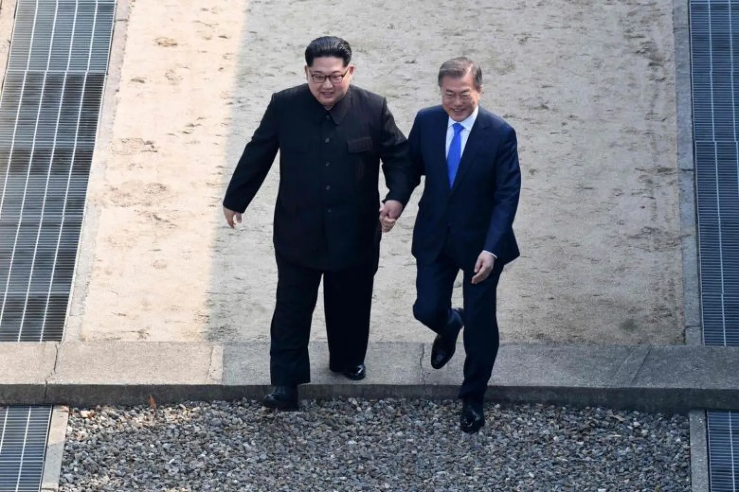 North Korea's leader Kim Jong Un (left) walks with South Korea's President Moon Jae In over the Military Demarcation Line that divides their countries as they meet at Panmunjom, on April 27, 2018. PHOTO: AFP
