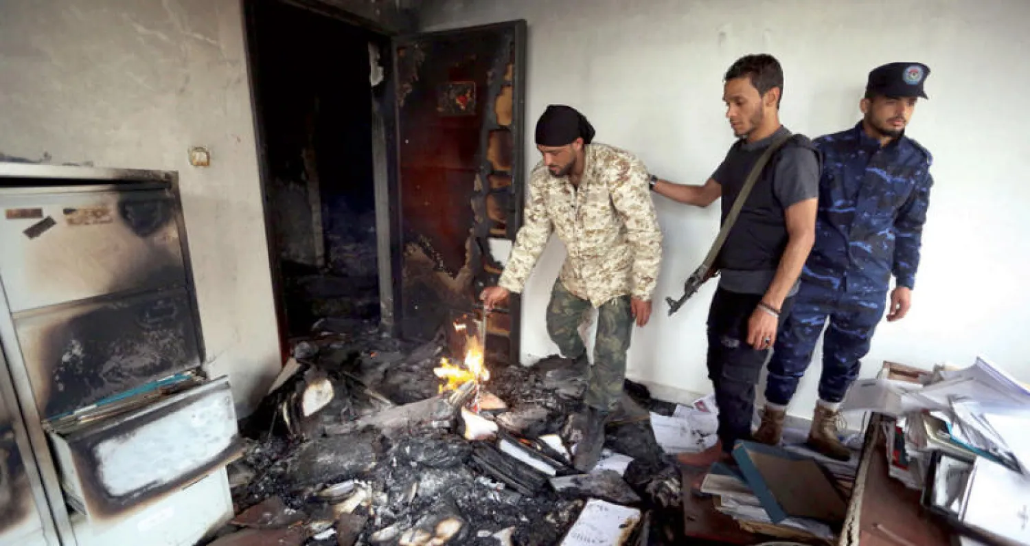 عناصر من الشرطة الليبية يعاينون الدمار الذي لحق بمقر مفوضية الانتخابات في العاصمة طرابلس أمس (أ.ف.ب)