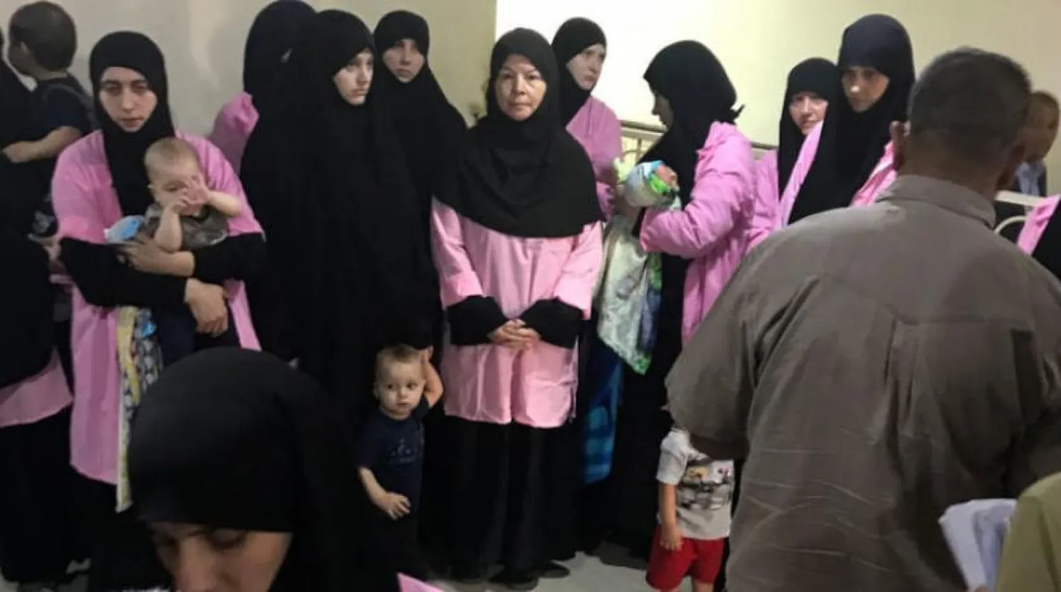 A picture taken on April 29, 2018 in the Iraqi capital Baghdad's Central Criminal Court shows women who have been sentenced to life in prison on grounds of joining ISIS standing with children in a hallway. Ammar Karim / AFP
