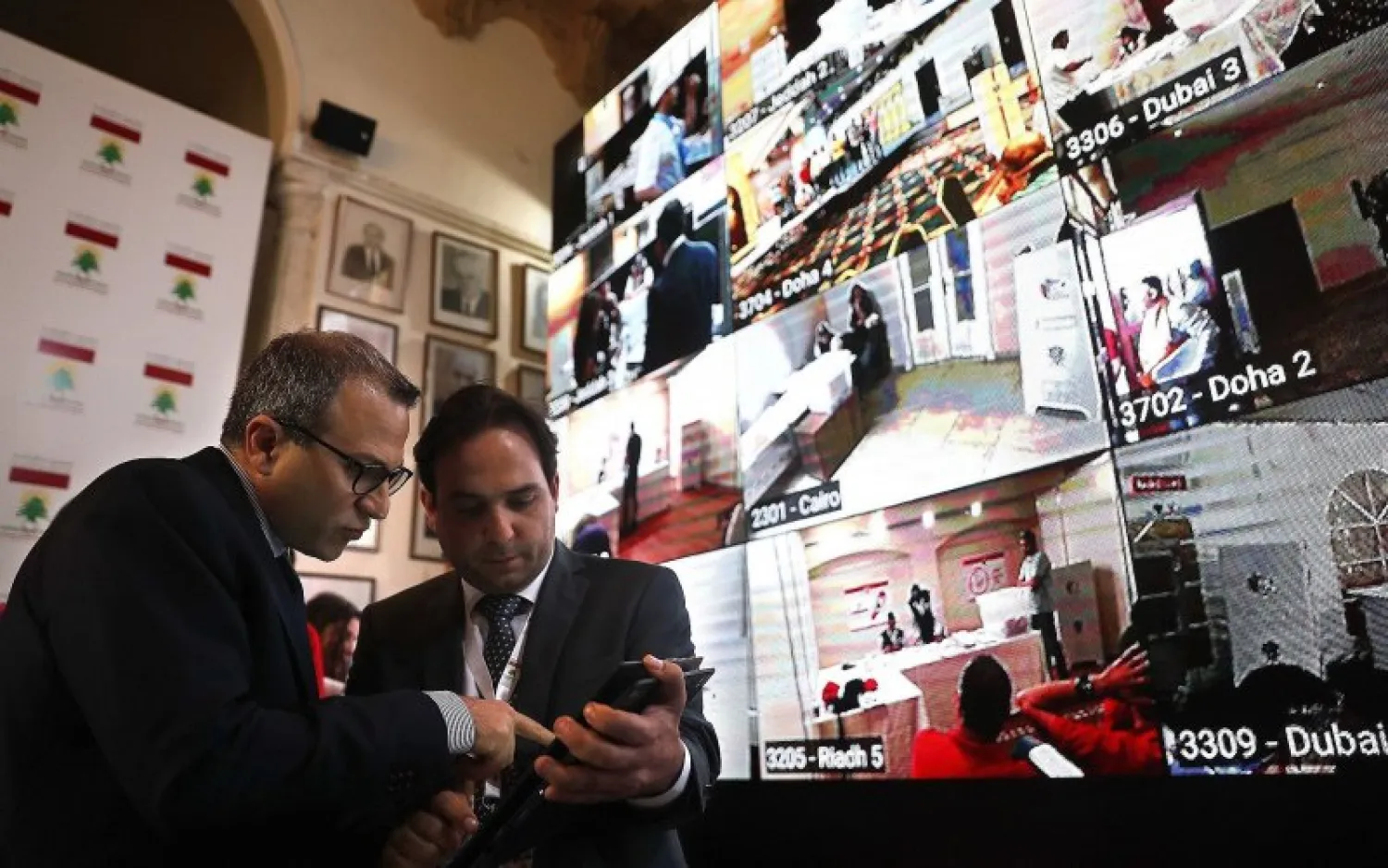 Lebanese Foreign Minister Jibran Bassil, left, talks with an assistant as they stand next to a giant screen following voting by Lebanese expatriates in six Arab countries, ahead of parliamentary elections scheduled to be held in Lebanon on May 6, at the Lebanese Foreign Ministry in Beirut, on April 27, 2018. (AP Photo/Hussein Malla)