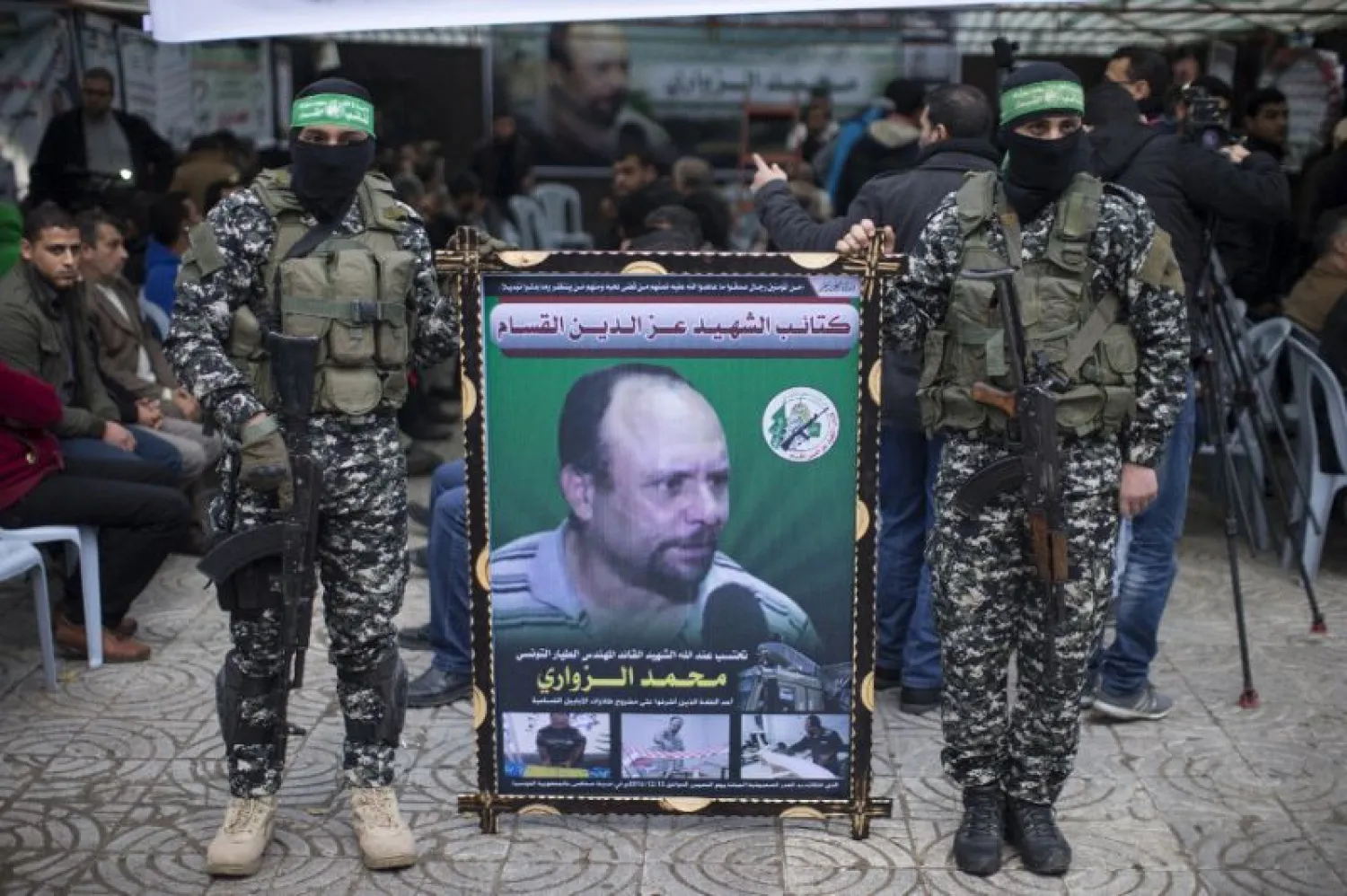 Members of the Ezzedine al-Qassam Brigades, the military wing of Hamas, hold a banner bearing a portrait of one of their leaders, Mohamed Zaouari, who was murdered in Tunisia, during a ceremony in his memory (AFP Photo/MAHMUD HAMS)
 