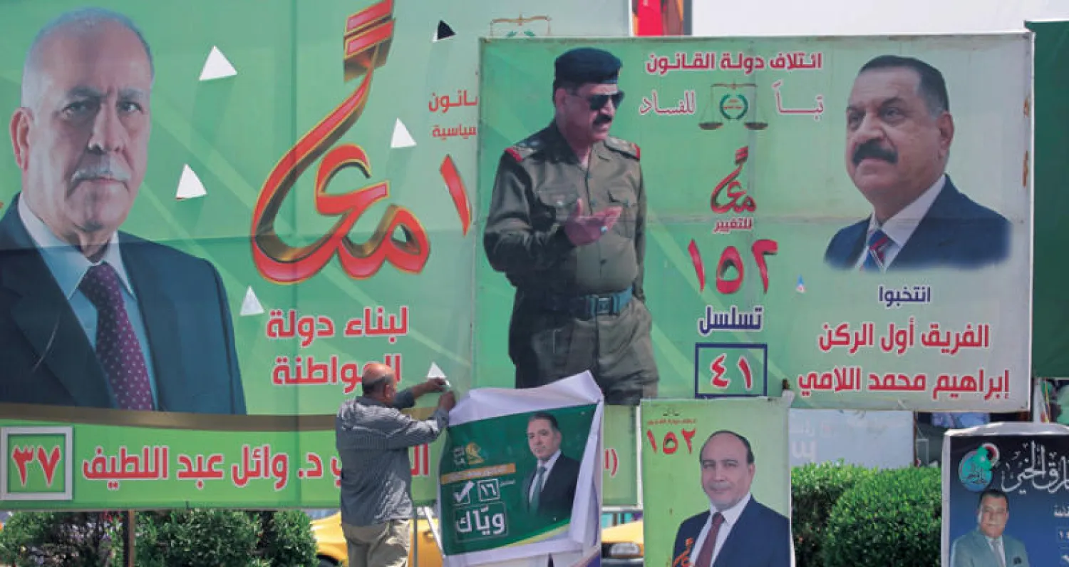 عراقي يعلق ملصقاً انتخابياً في بغداد أمس (أ.ف.ب)