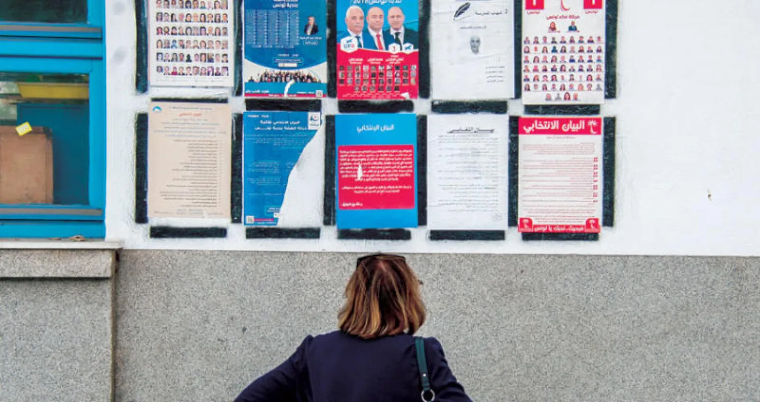 تونسية تلقي نظرة على دعايات انتخابية في العاصمة تونس أمس (أ.ب)