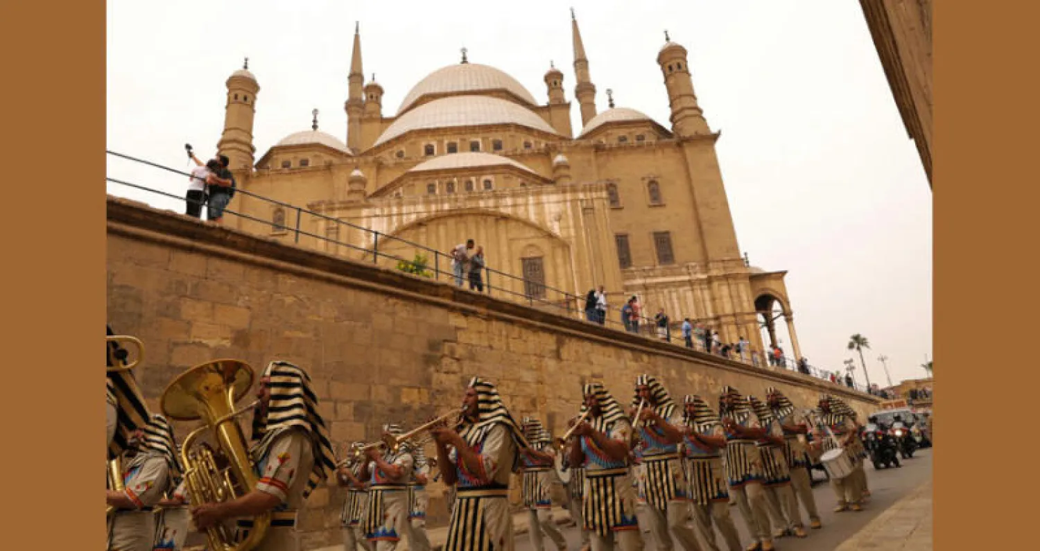 مصريون يرتدون أزياء فرعونية أمام قلعة القاهرة خلال حفل نقل عجلة توت عنخ آمون من المتحف العسكري إلى المتحف المصري الكبير (أ.ف.ب)