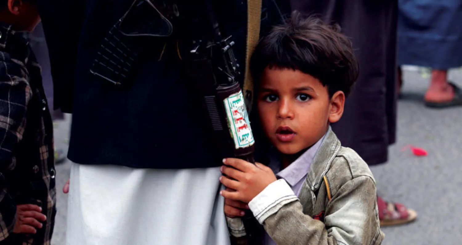 طفل مع والده في تجمع حوثي مسلح في صنعاء (إ.ب.أ)