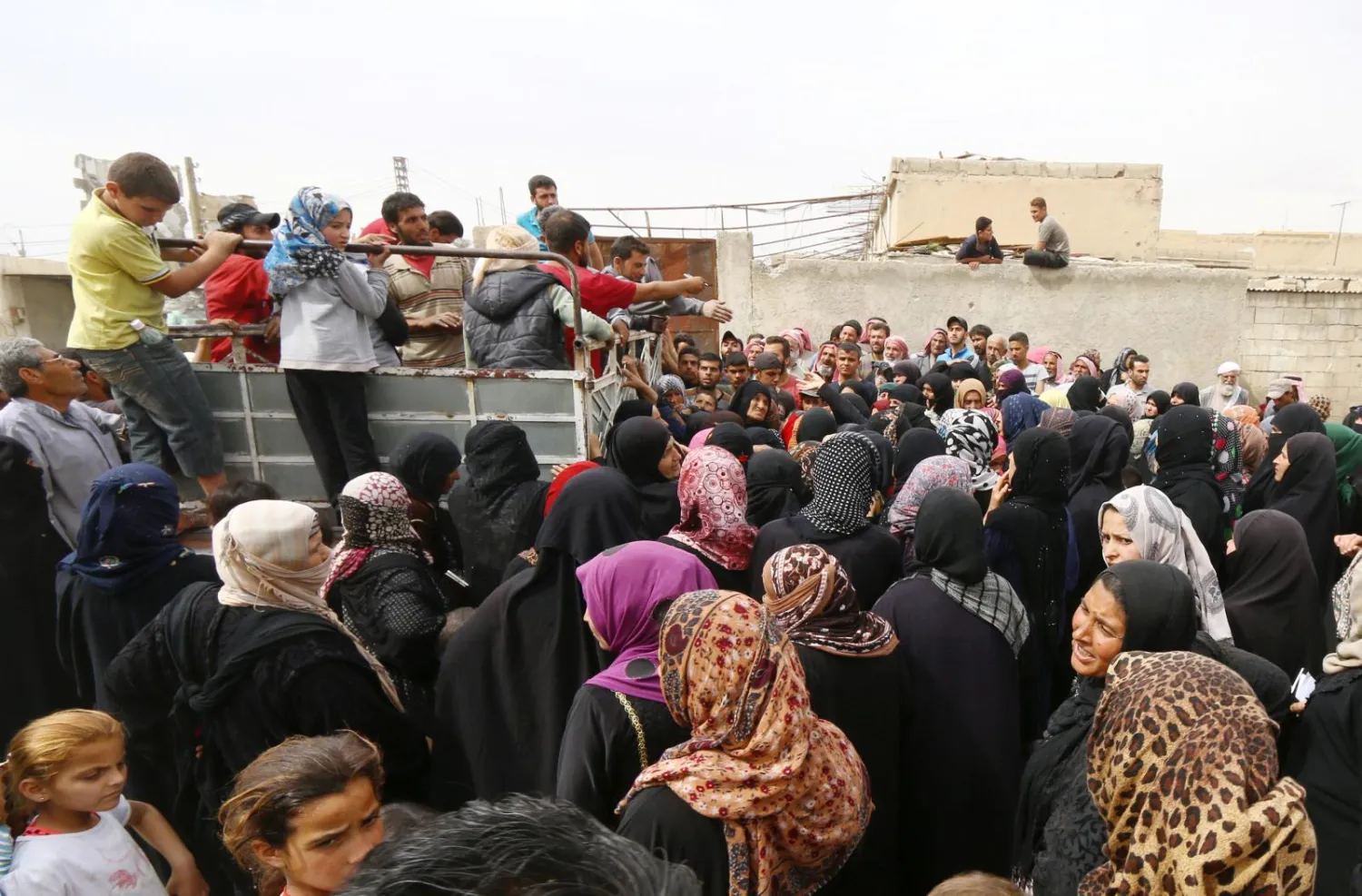 People gather around a truck carrying food aid given by UN's World Food Programme in Raqqa, Syria April 26, 2018. REUTERS/Aboud Hamam
