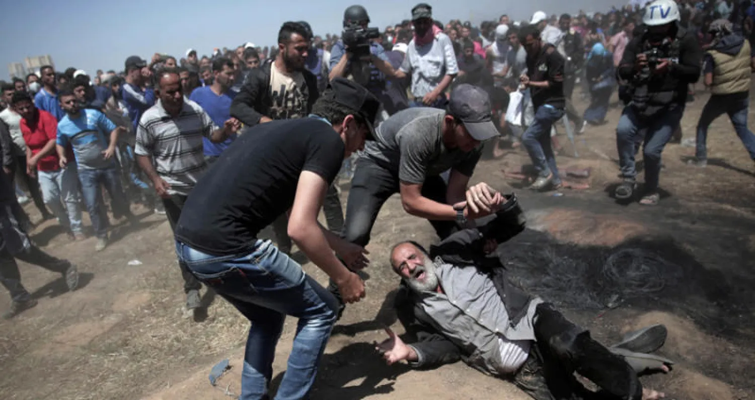 يسعفون مسناً فلسطينياً سقط أرضاً خلال مواجهات مع الجنود الإسرائيليين شرق خانيونس في قطاع غزة أمس (أ.ب)