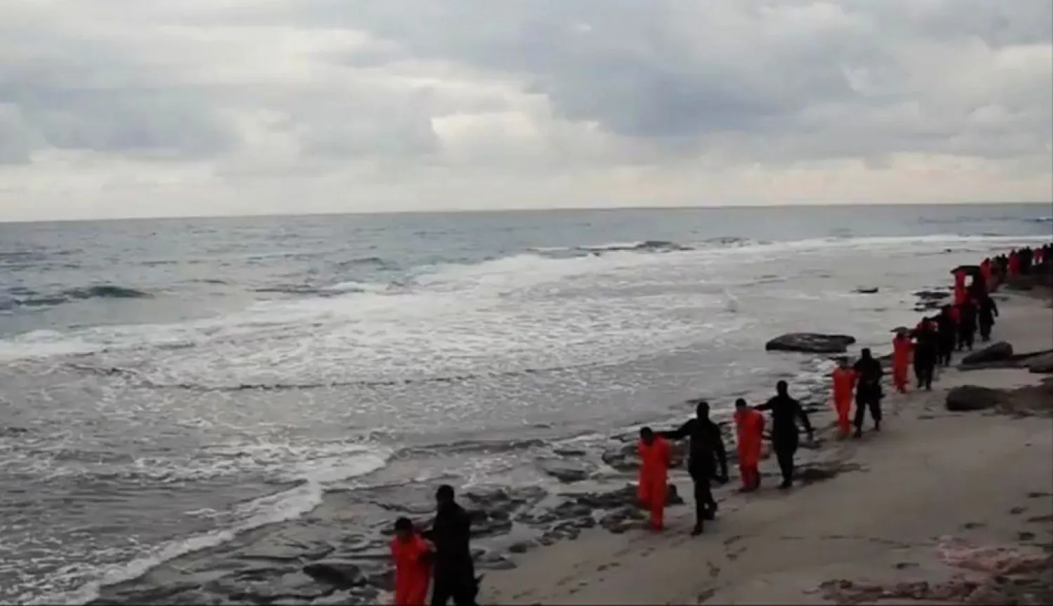 Egyptian Coptic Christians in orange jumpsuits being led along a beach, each accompanied by a masked ISIS terrorist, before they are beheaded. (AP)