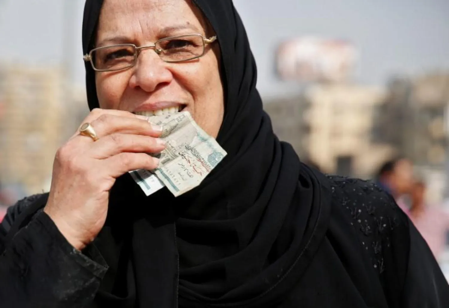 An Egyptian woman holds her money in her mouth at a market in Cairo, Egypt October 14, 2016. REUTERS/Amr Abdallah Dalsh
