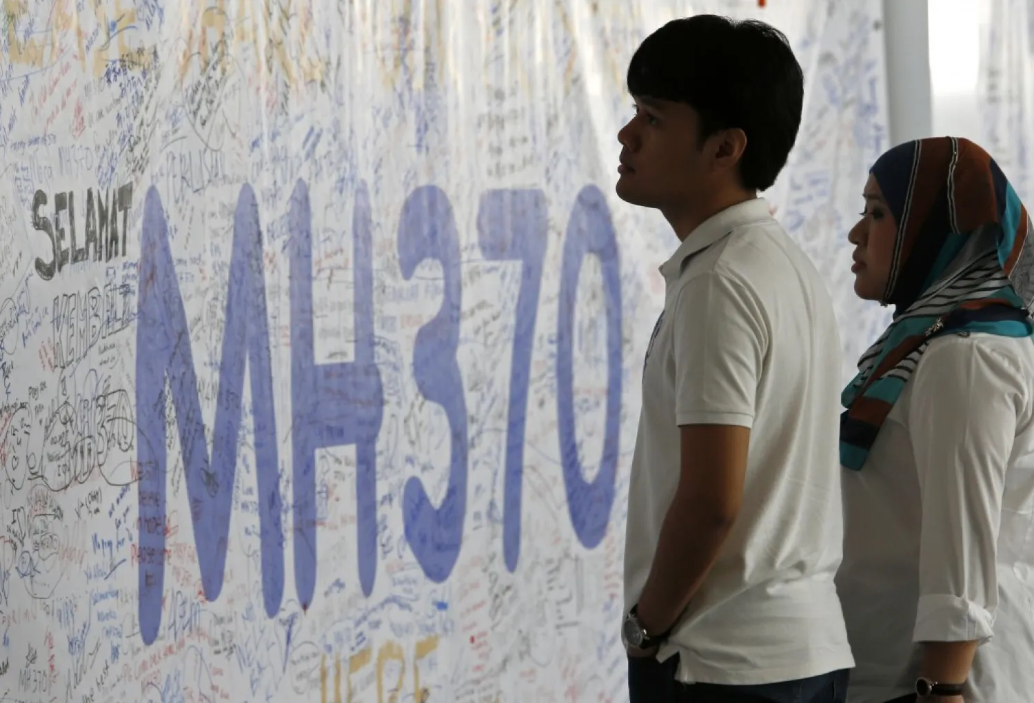 People look at a banner signed by well-wishers for the passengers of the Malaysia Airlines MH370 plane at Kuala Lumpur International Airport in 2014. (Reuters)