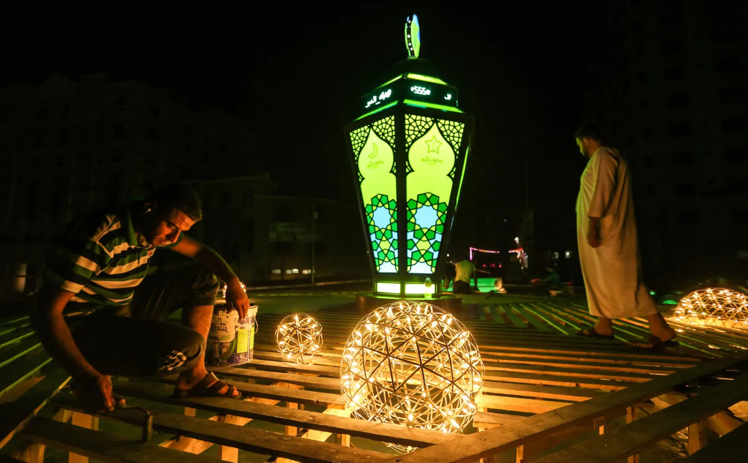 رجل يثبت فوانيس رمضان في مدينة غزة بفلسطين