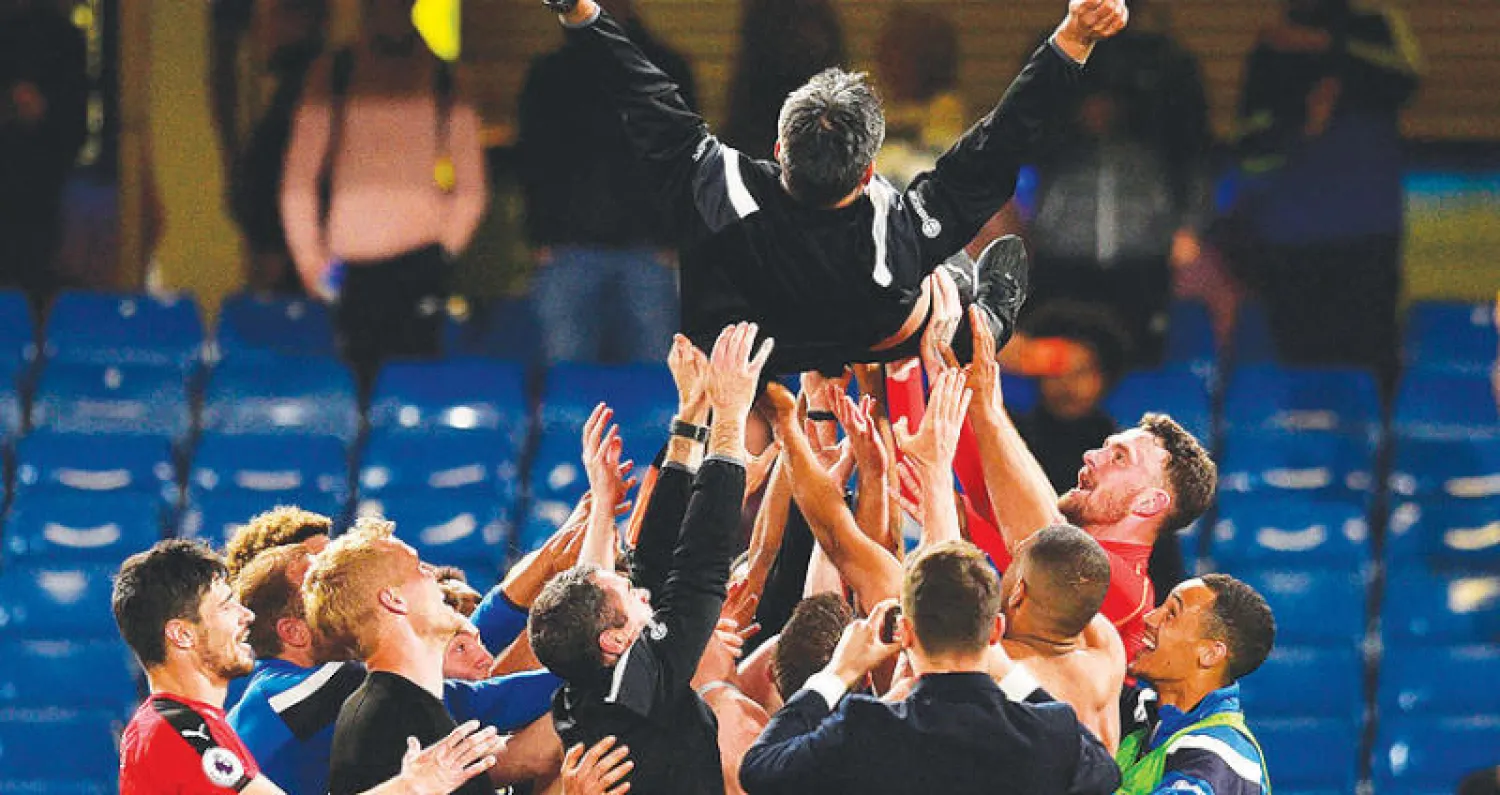 لاعبو هيدرسفيلد وأعضاء في الجهاز الفني يحملون المدرب فاغنر احتفالا بالبقاء في الدوري الممتاز (أ.ف.ب)