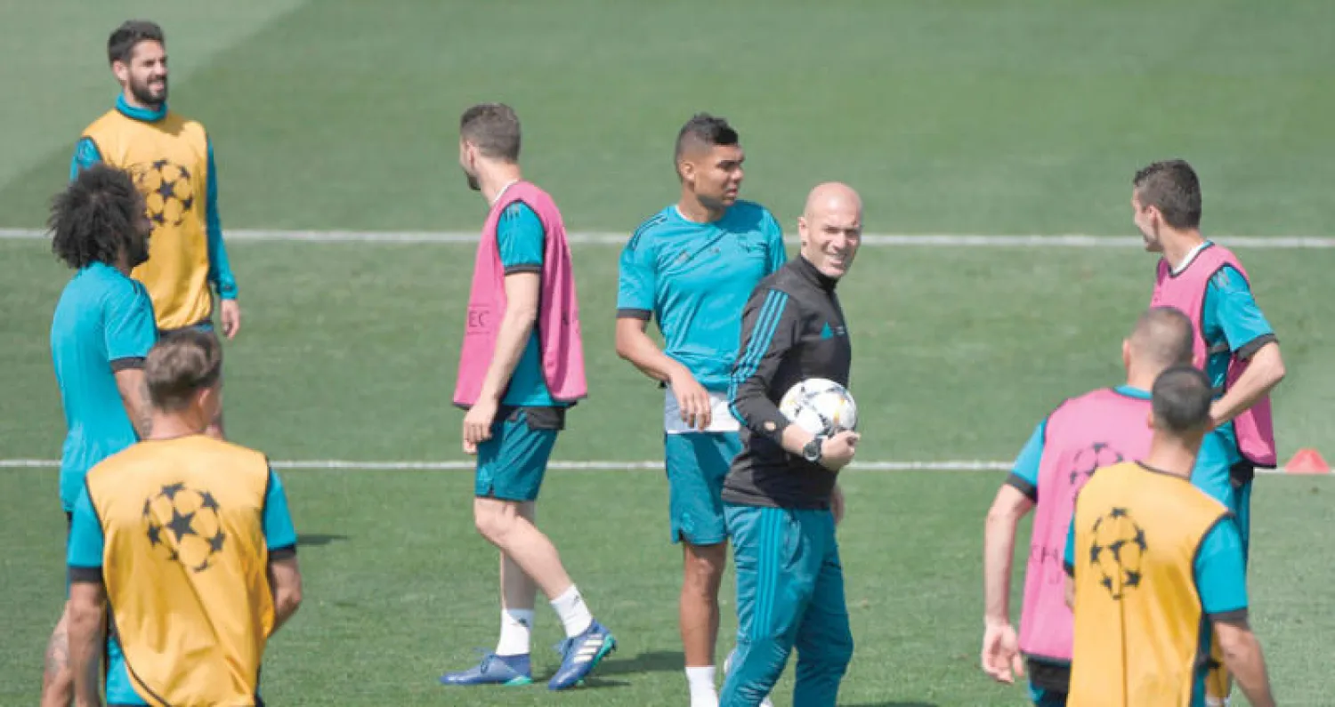 زيدان محاطاً بلاعبي ريال مدريد في المران أمس استعداداً لنهائي دوري الأبطال (أ.ف.ب)