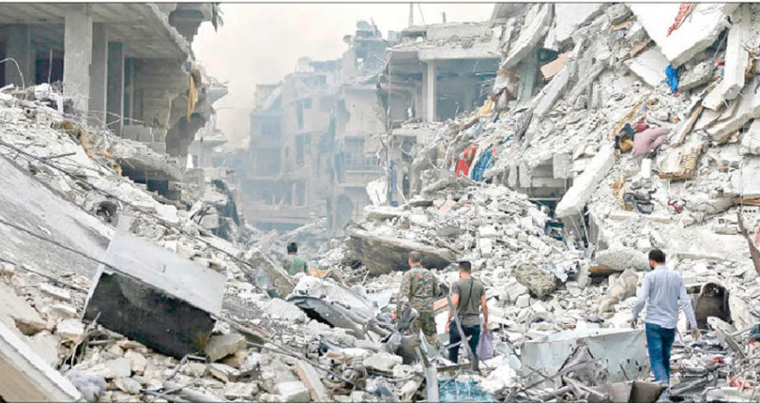 مسلحون موالون للنظام وسط الخراب في «الحجر الأسود» جنوب دمشق أمس (أ.ف.ب)