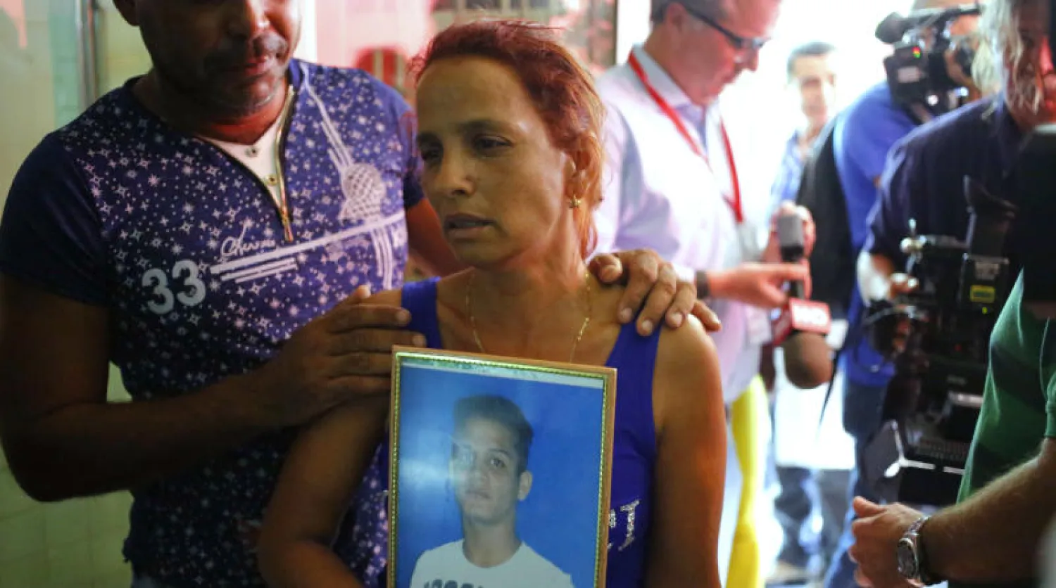 سيدة تحمل صورة لابنها الذي توفي جراء تحطم الطائرة في كوبا (أ.ب)