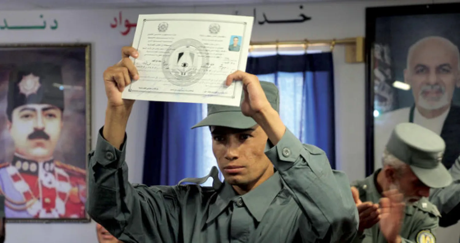 جندي أفغاني يرفع شهادة تخرجه في الأكاديمية العسكرية بقندهار أمس (إ.ب.أ)