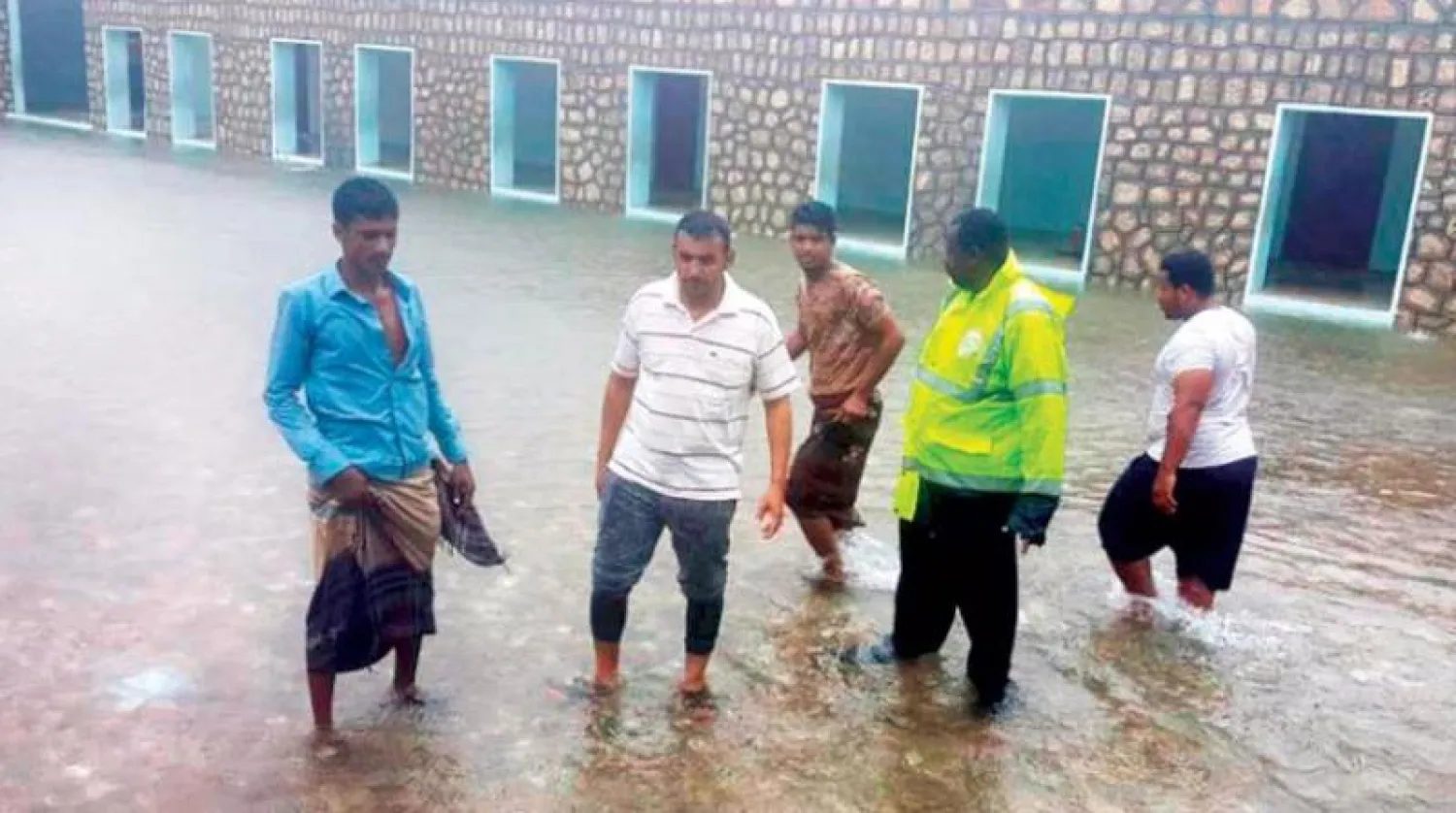 أرشيفيى لرجال يقفون وسط مياه الفياضانات في حديبو عاصمة محافظة سقطرى المنكوبة (أ.ب)