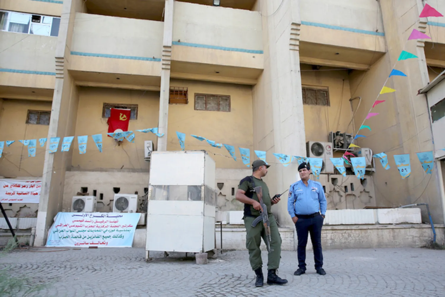 An Iraqi policeman and a soldier stand guard the headquarters in Baghdad of the Iraqi Communist Party after two bombs exploded there (AFP)