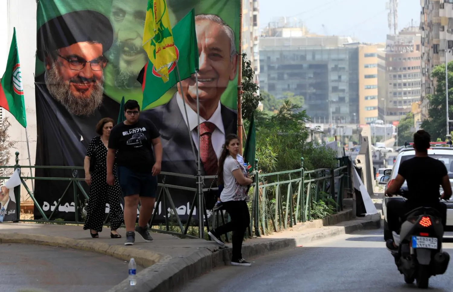 People walk past a campaign banner showing Lebanese Parliament Speaker and candidate for parliamentary election Nabih Berri and Hezbollah's Secretary-General   Hassan Nasrallah in Beirut, Lebanon May 4, 2018. REUTERS/Jamal Saidi
