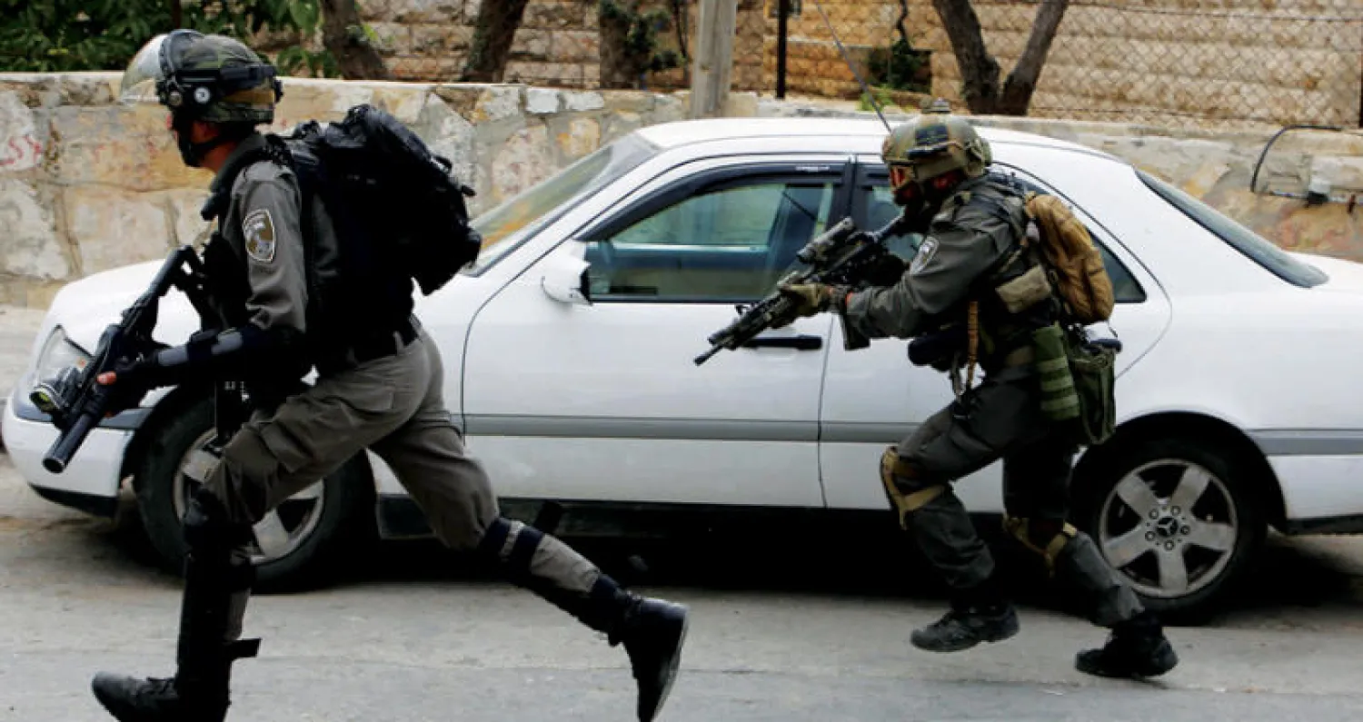 اثنان من جنود الاحتلال الإسرائيلي أثناء اقتحام مخيم الأمعري بالضفة الغربية فجر أمس (أ.ف.ب)