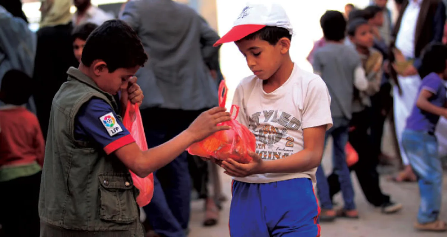 أطفال يمنيون يتلقون حصصاً غذائية وزعتها مؤسسة خيرية بمناسبة رمضان في صنعاء (أ.ف.ب)