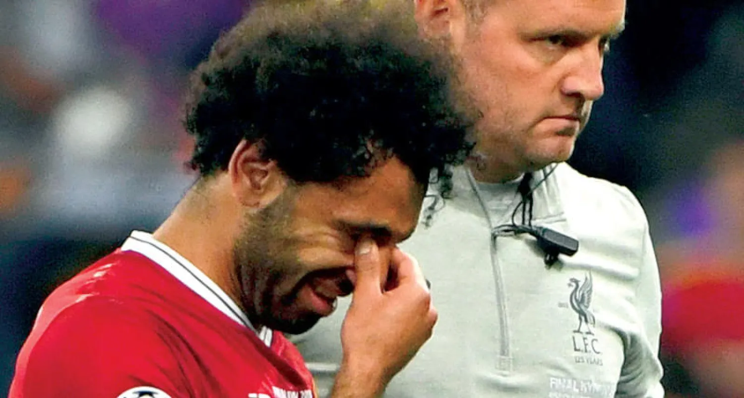 صلاح بصحبة طبيب ليفربول لحظة خروجه من نهائي أوروبا مصاباً (أ.ف.ب)