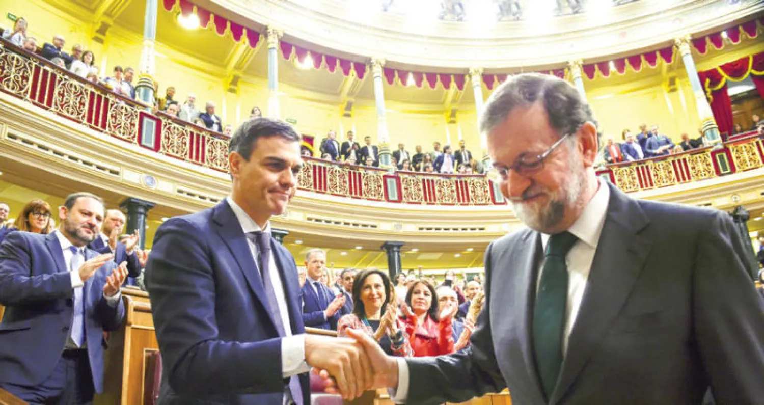 ماريانو راخوي المهزوم (يمين) يصافح ويهنِّئ خصمه السياسي الاشتراكي المنتصر بيدرو سانشيز بعد تمرير مشروع سحب الثقة في البرلمان (رويترز)