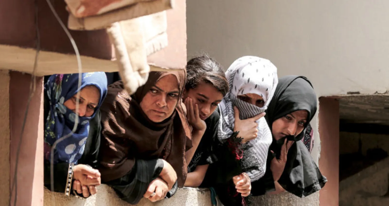 نسوة يتابعن من على شرفة منزل مراسم تشييع المسعفة رزان النجار في خانيونس أمس (أ.ف.ب)