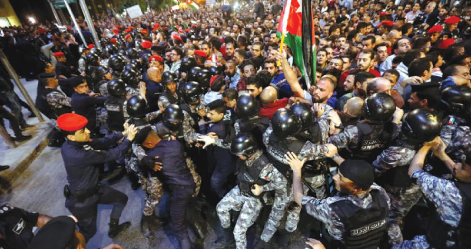 اشتباكات بين رجال شرطة ومتظاهرين أمام مكتب رئيس الوزراء في عمّان أمس (رويترز)