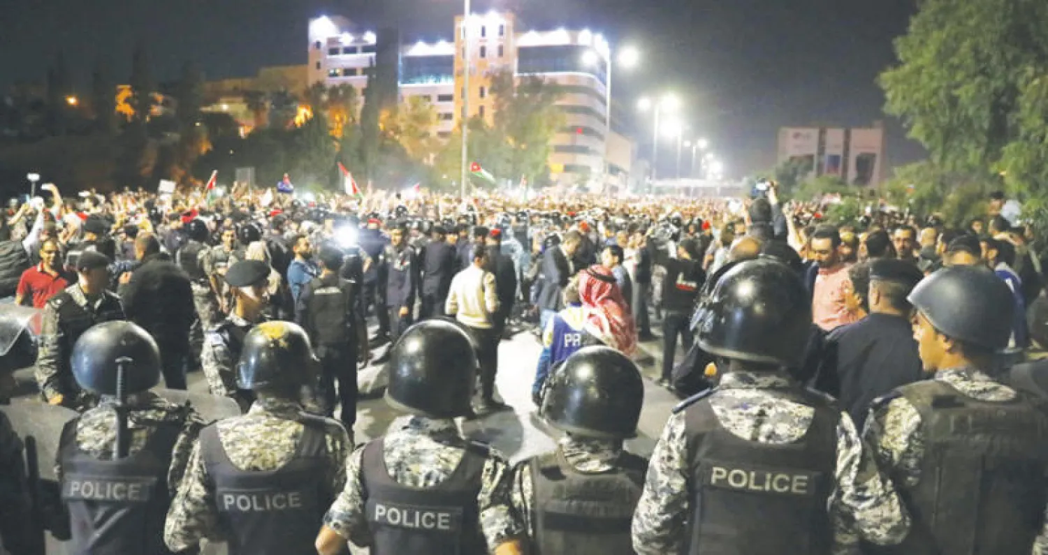 قوات الأمن الأردنية تعترض متظاهرين احتجاجاً على قانون ضريبة الدخل في عمّان (إ.ب.أ)